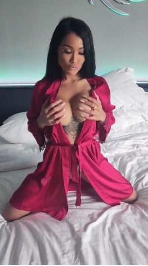 Гламурная брюнетка в халате сидит на кроватке и трясет большими сисяками